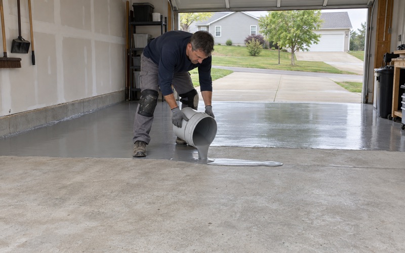 Mixed epoxy poured in a ribbon onto the ground slab of an Iowa City garage, the first coat starting at the back wall.