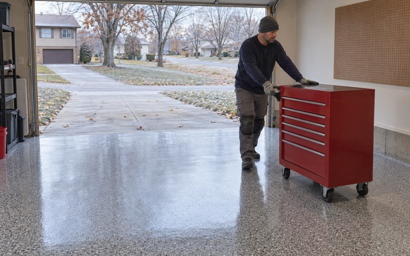 A rolling tool chest wheeled back onto a same-day polyaspartic flake floor in an Iowa City garage on a cold autumn afternoon.